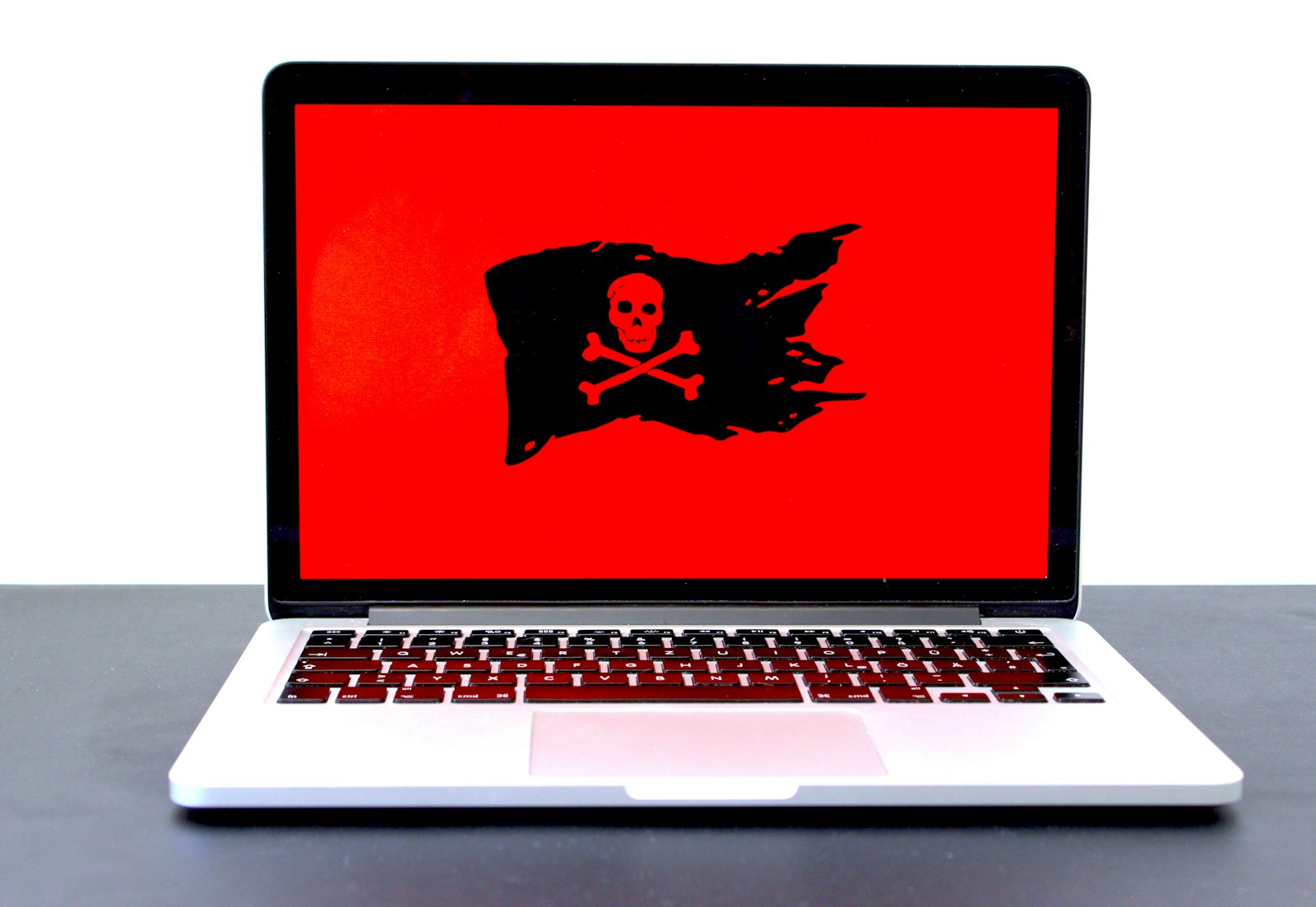 macbook pro z wyświetloną piracką flagą na czerwonym tle